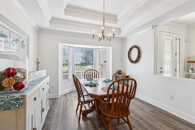 dining area featuring a notable chandelier, ornamental molding, a tray ceiling, baseboards, and dark wood-style flooring