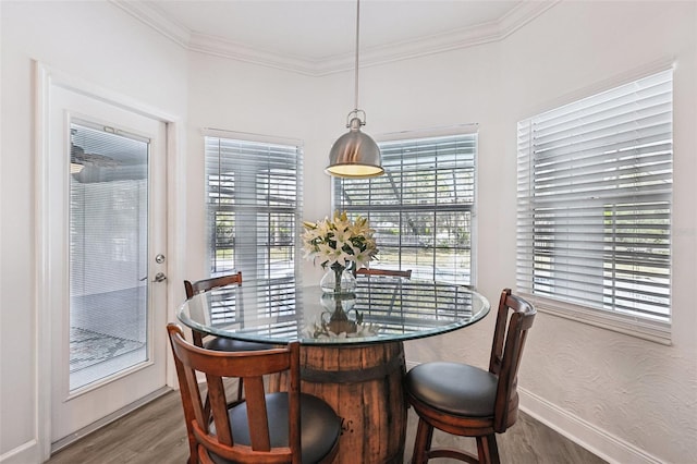 dining room with crown molding, wood finished floors, and baseboards