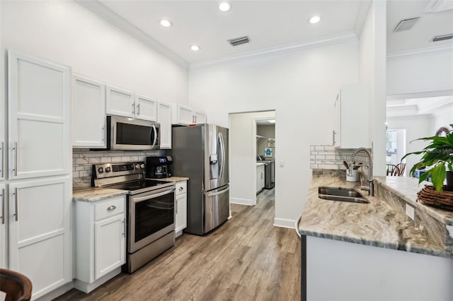 kitchen with crown molding, white cabinets, appliances with stainless steel finishes, and a sink