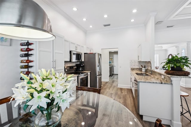 kitchen with visible vents, a sink, a kitchen breakfast bar, stainless steel appliances, and a peninsula