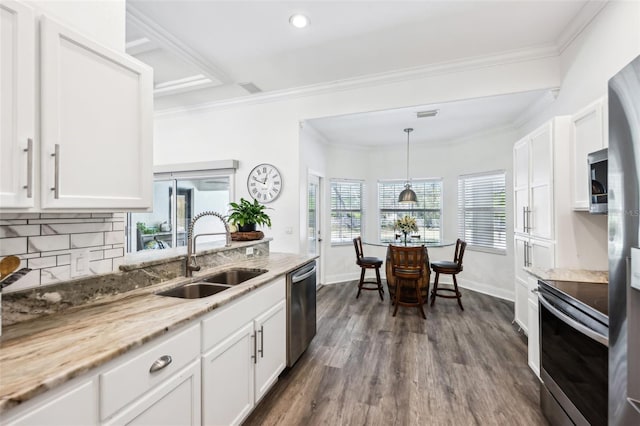 kitchen with light stone countertops, ornamental molding, appliances with stainless steel finishes, white cabinets, and a sink