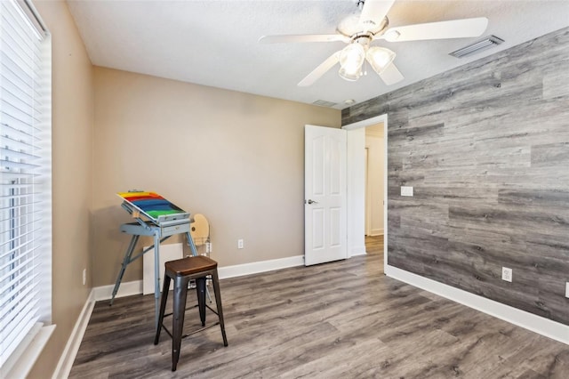 game room featuring visible vents, wood finished floors, wood walls, baseboards, and ceiling fan