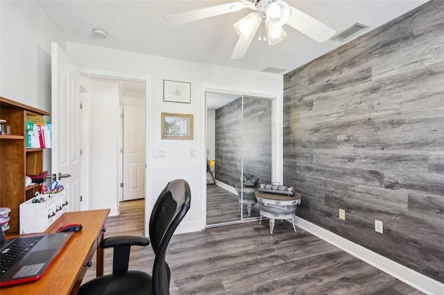 office area with visible vents, a ceiling fan, wood finished floors, wood walls, and baseboards