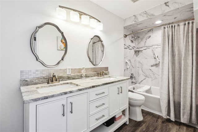 full bath with a sink, double vanity, wood finished floors, and shower / tub combo