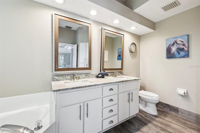 bathroom with visible vents, toilet, wood finished floors, and a sink