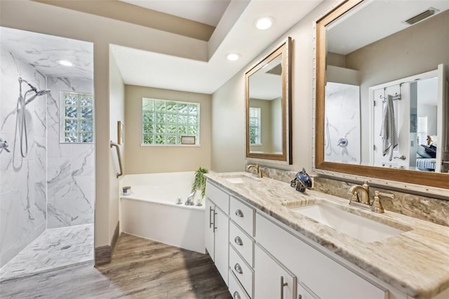 bathroom with wood finished floors, visible vents, a marble finish shower, a sink, and a garden tub