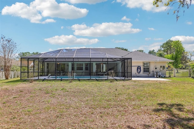 rear view of property featuring stucco siding, a lawn, glass enclosure, a fenced backyard, and a patio area