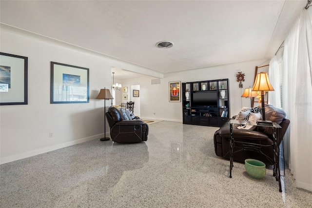 living area featuring speckled floor, baseboards, a notable chandelier, and visible vents