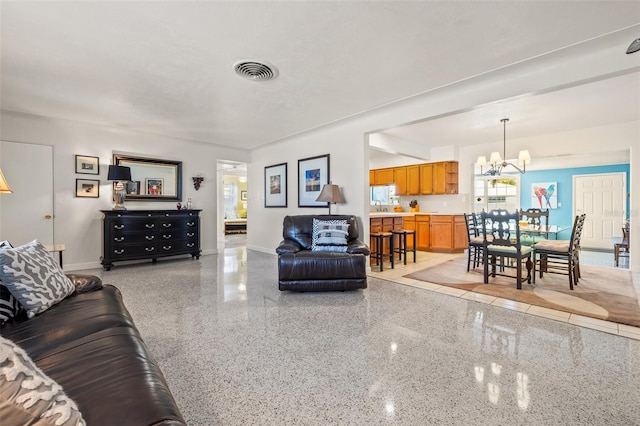 living room featuring visible vents, light speckled floor, a notable chandelier, and baseboards