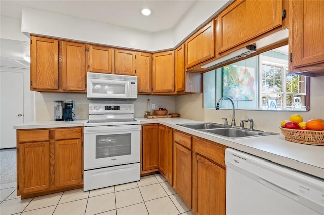 kitchen featuring brown cabinetry, white appliances, light countertops, and a sink