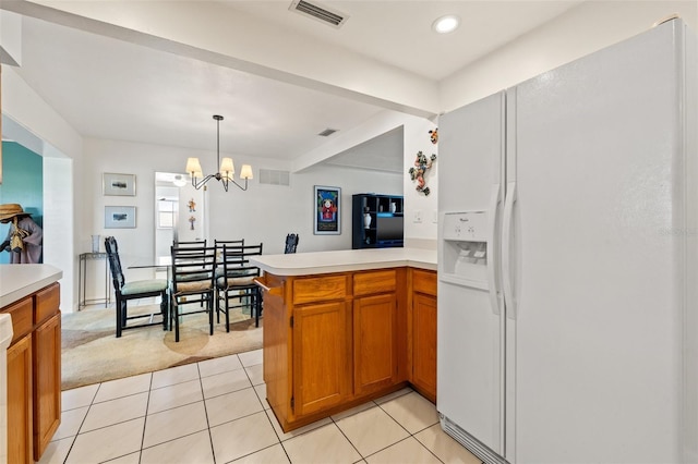 kitchen featuring light tile patterned floors, visible vents, light countertops, white fridge with ice dispenser, and brown cabinets