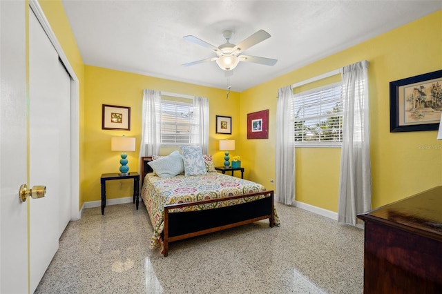 bedroom featuring speckled floor, multiple windows, baseboards, and ceiling fan