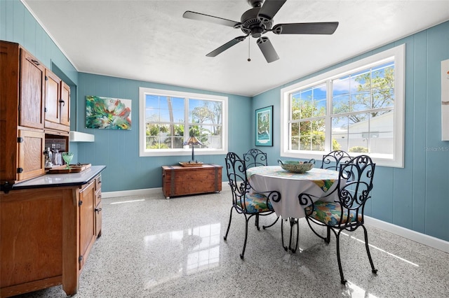 dining room featuring a wealth of natural light, speckled floor, baseboards, and a ceiling fan