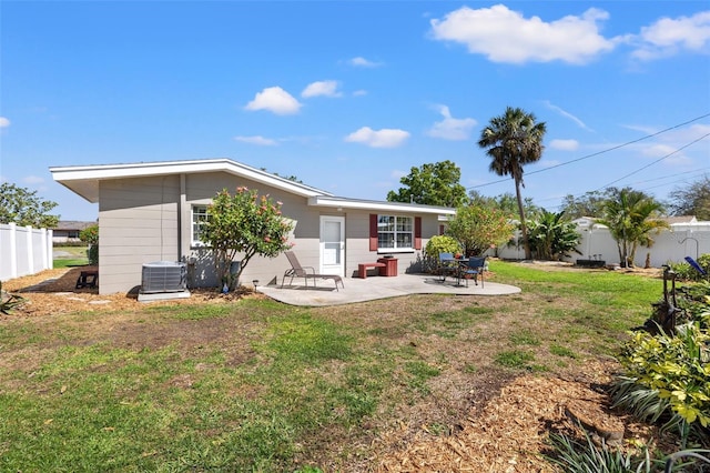 rear view of house with a fenced backyard, central air condition unit, a yard, and a patio