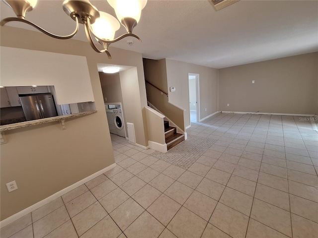 unfurnished room featuring visible vents, washer / clothes dryer, stairway, light tile patterned floors, and baseboards