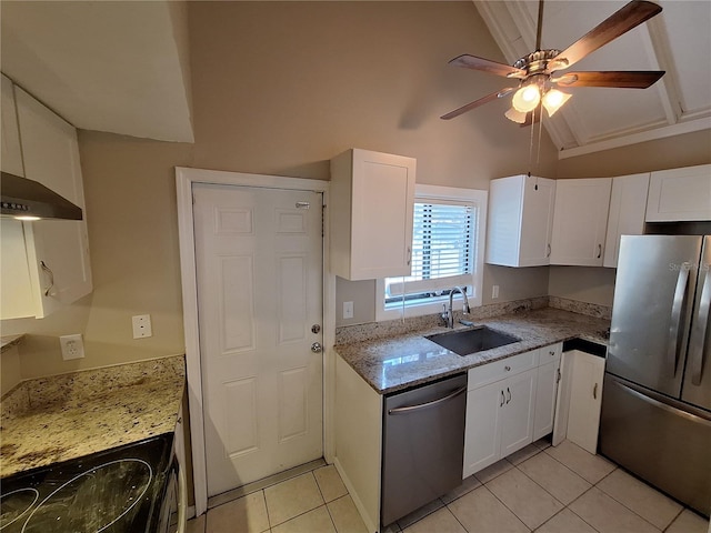 kitchen with light tile patterned floors, a sink, vaulted ceiling, white cabinets, and appliances with stainless steel finishes