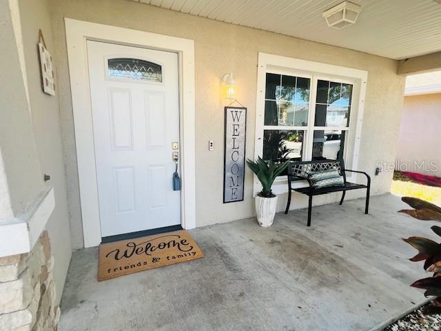 doorway to property with stucco siding and covered porch