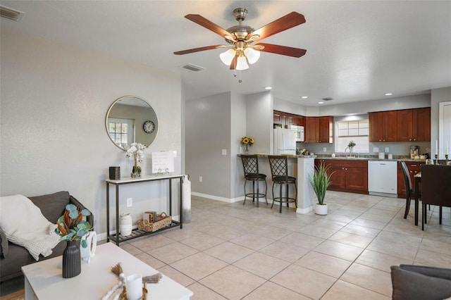 living room with light tile patterned floors, visible vents, and baseboards