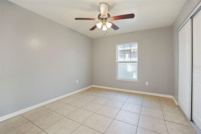 unfurnished bedroom featuring a ceiling fan, light tile patterned floors, baseboards, and a closet