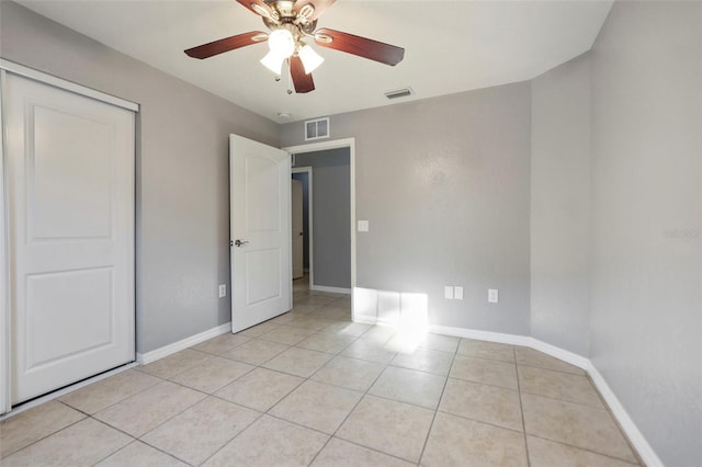 unfurnished bedroom featuring light tile patterned flooring, baseboards, visible vents, and a closet