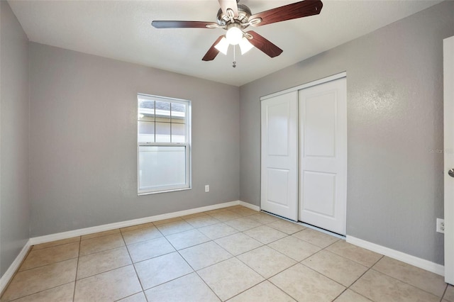 unfurnished bedroom with light tile patterned floors, a closet, and baseboards