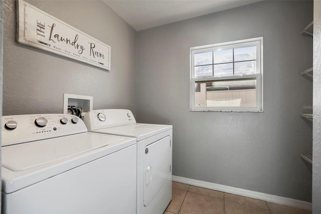 washroom featuring baseboards, light tile patterned flooring, laundry area, and washing machine and clothes dryer