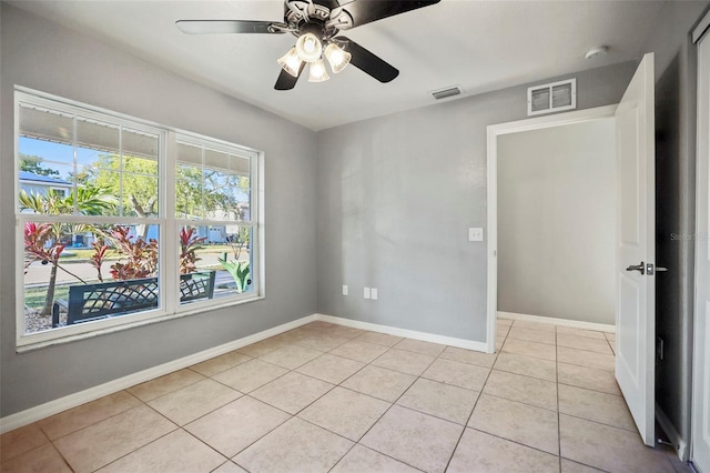 empty room with light tile patterned floors, baseboards, visible vents, and ceiling fan