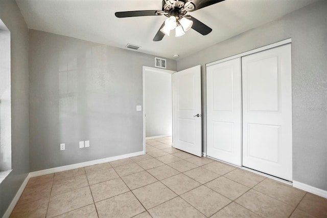 unfurnished bedroom with light tile patterned floors, visible vents, a closet, and baseboards