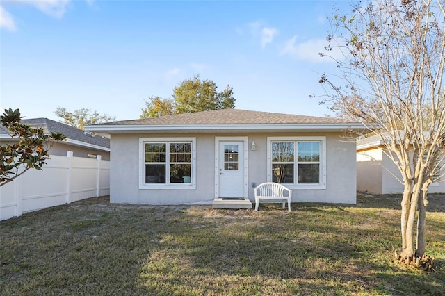 view of front of property with stucco siding, a front yard, and fence