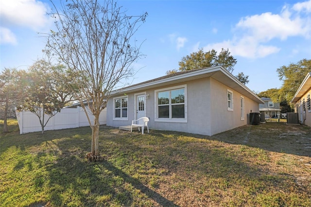 ranch-style house with a front yard, cooling unit, fence, and stucco siding