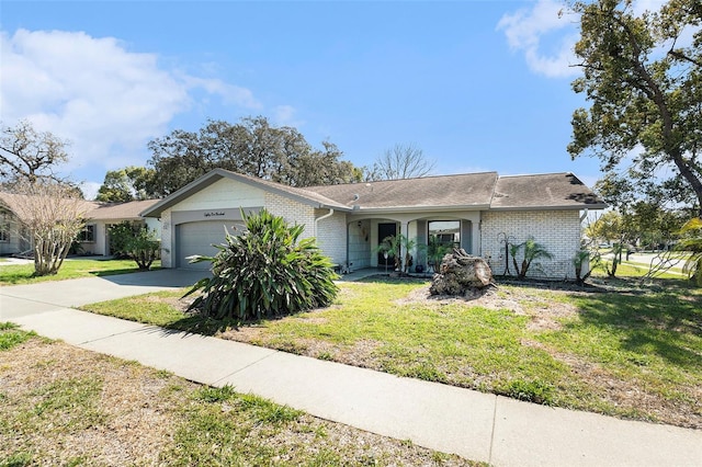 view of front of house with a front yard, brick siding, a garage, and driveway