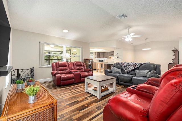 living area with wood finished floors, a ceiling fan, visible vents, lofted ceiling, and a textured ceiling