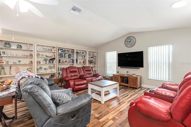 living area featuring vaulted ceiling, wood finished floors, visible vents, and a healthy amount of sunlight