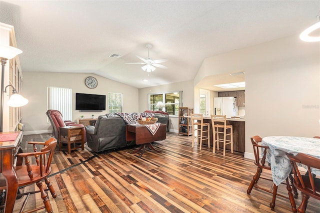 living room featuring visible vents, wood finished floors, baseboards, ceiling fan, and vaulted ceiling