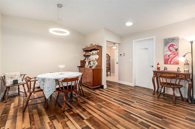 dining space with a textured ceiling, baseboards, lofted ceiling, and wood finished floors