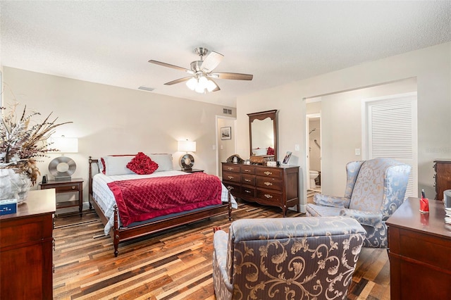 bedroom featuring wood finished floors, visible vents, and a textured ceiling