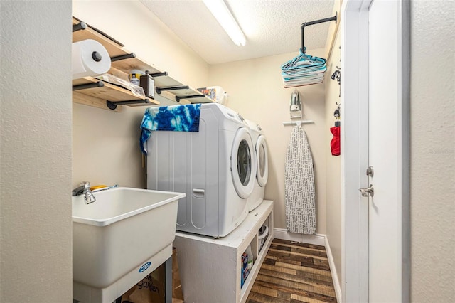 washroom featuring a sink, washing machine and dryer, laundry area, a textured ceiling, and dark wood-style flooring