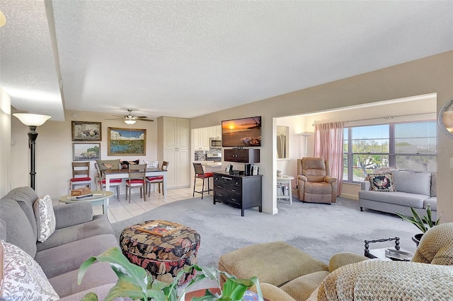 living room featuring light tile patterned floors, light carpet, a textured ceiling, and a ceiling fan