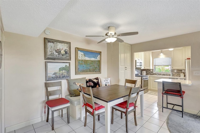 dining room featuring a textured ceiling, light tile patterned flooring, baseboards, and ceiling fan