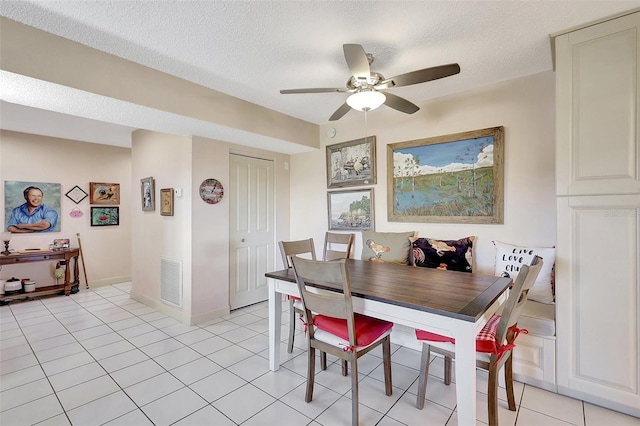 dining room featuring visible vents, a textured ceiling, light tile patterned floors, baseboards, and ceiling fan