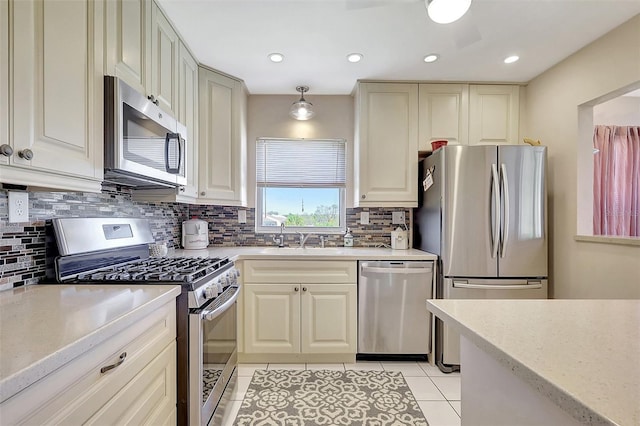 kitchen featuring tasteful backsplash, light stone countertops, light tile patterned flooring, stainless steel appliances, and a sink