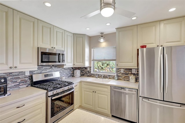 kitchen with light countertops, decorative backsplash, appliances with stainless steel finishes, light tile patterned flooring, and a sink