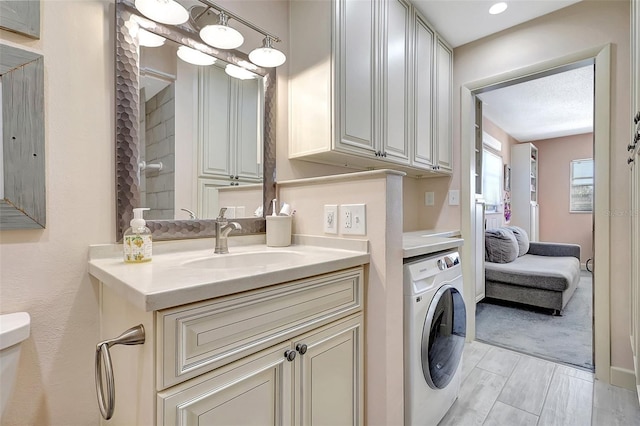 laundry area with laundry area, washer / clothes dryer, light wood-type flooring, and a sink