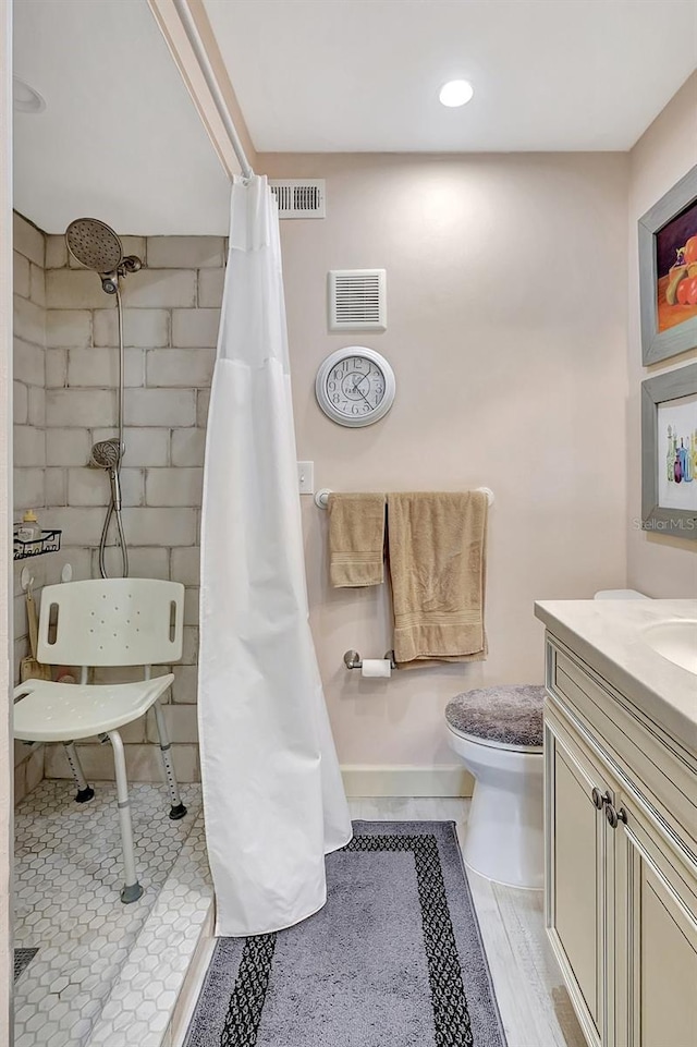 bathroom featuring vanity, toilet, visible vents, and tiled shower