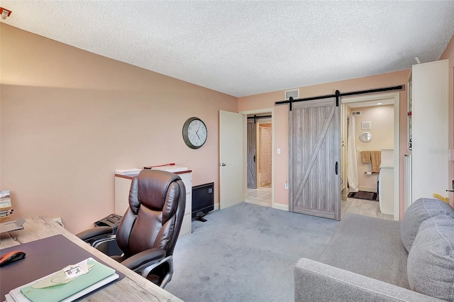 carpeted office with a barn door, a textured ceiling, and visible vents