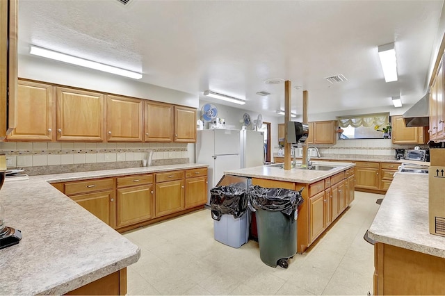 kitchen with light countertops, tasteful backsplash, visible vents, and a sink