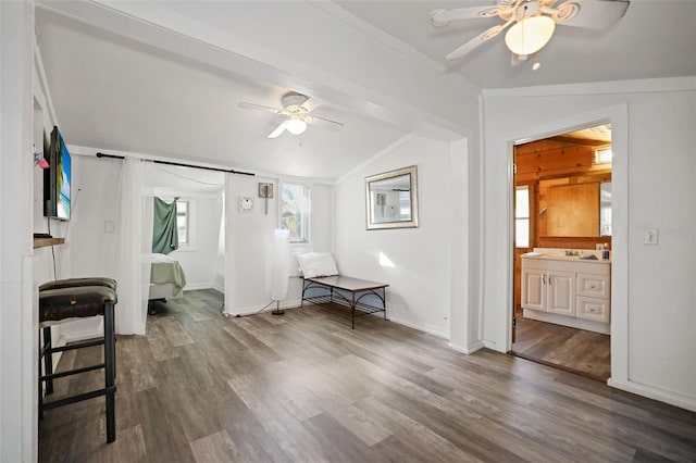 interior space with wood finished floors, ensuite bath, ceiling fan, vaulted ceiling, and crown molding