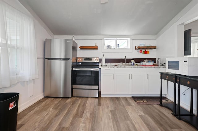 kitchen featuring open shelves, wood finished floors, appliances with stainless steel finishes, and a sink