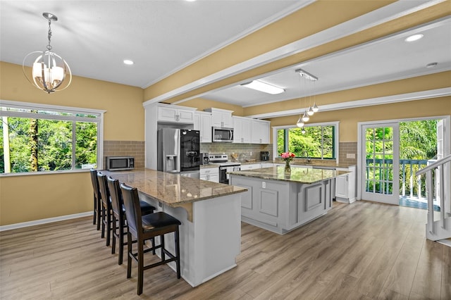 kitchen featuring tasteful backsplash, appliances with stainless steel finishes, light wood-type flooring, and a peninsula