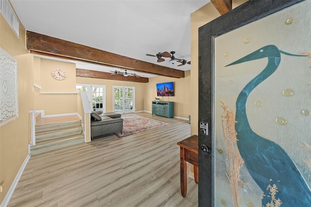 living area with beamed ceiling, visible vents, wood finished floors, stairway, and baseboards